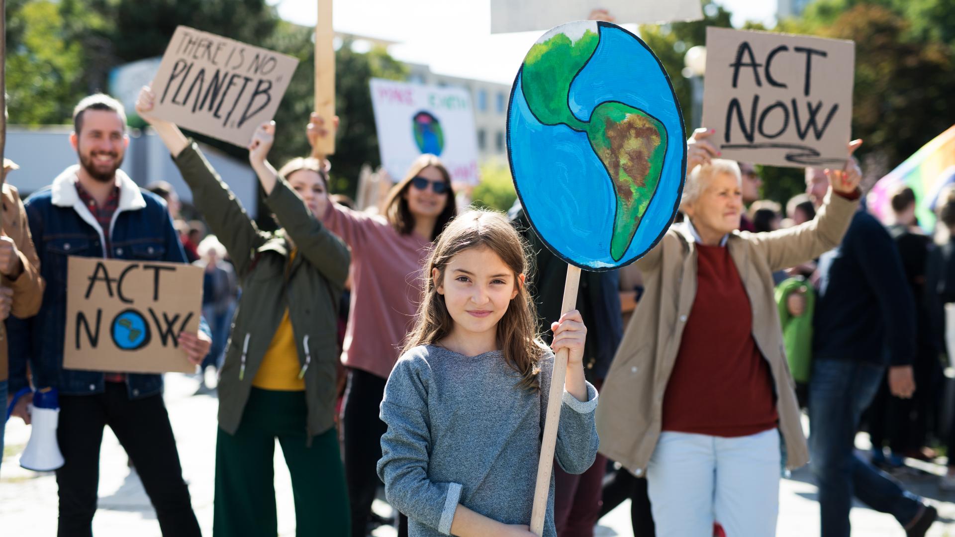 Een meisje met een bord van de aarde bij een groep mensen die actievoeren voor het klimaat